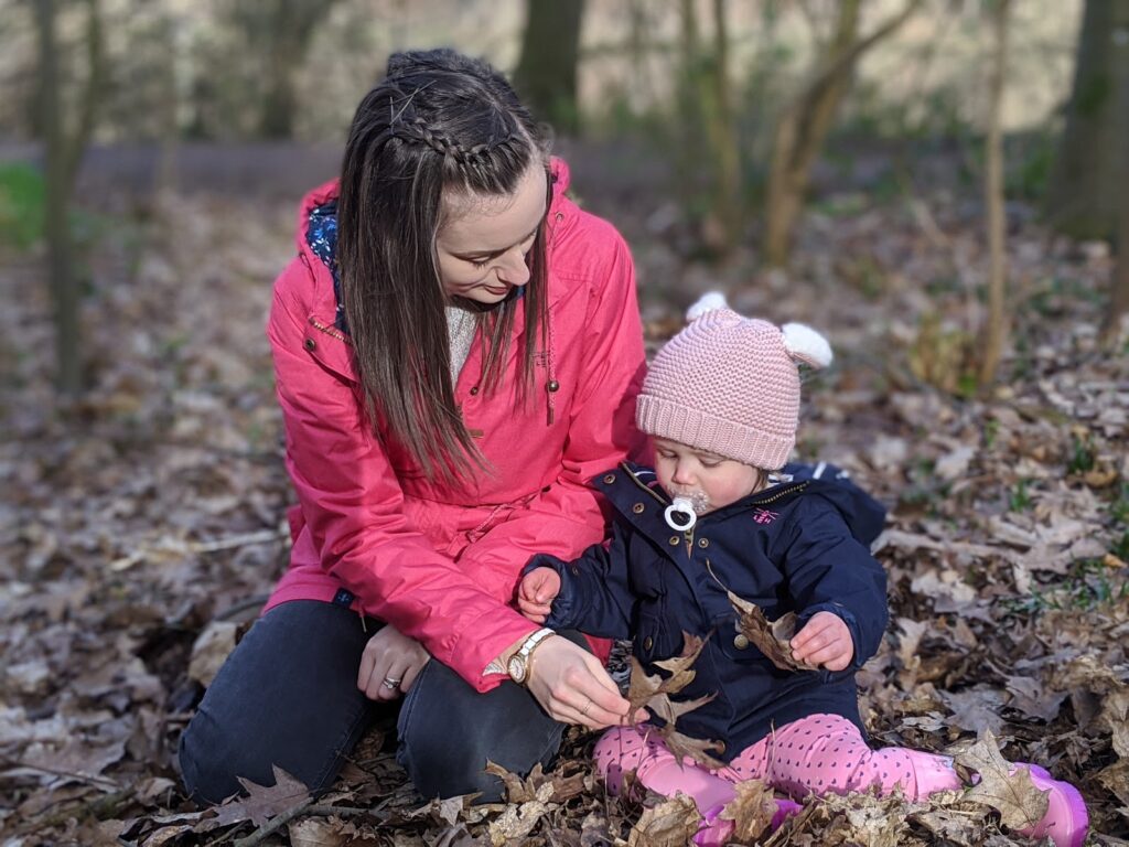 Mother & Daughter wearing Lighthouse raincoats sat in woodland scene. Woodland walks with Lighthouse Clothing.