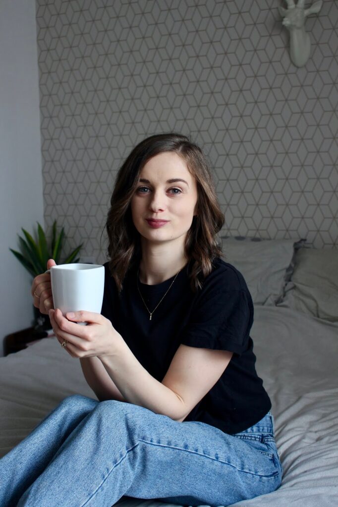 Little things that make you feel like you have your shit together. Lifestyle image of Claire sitting on bed drinking cup of coffee.