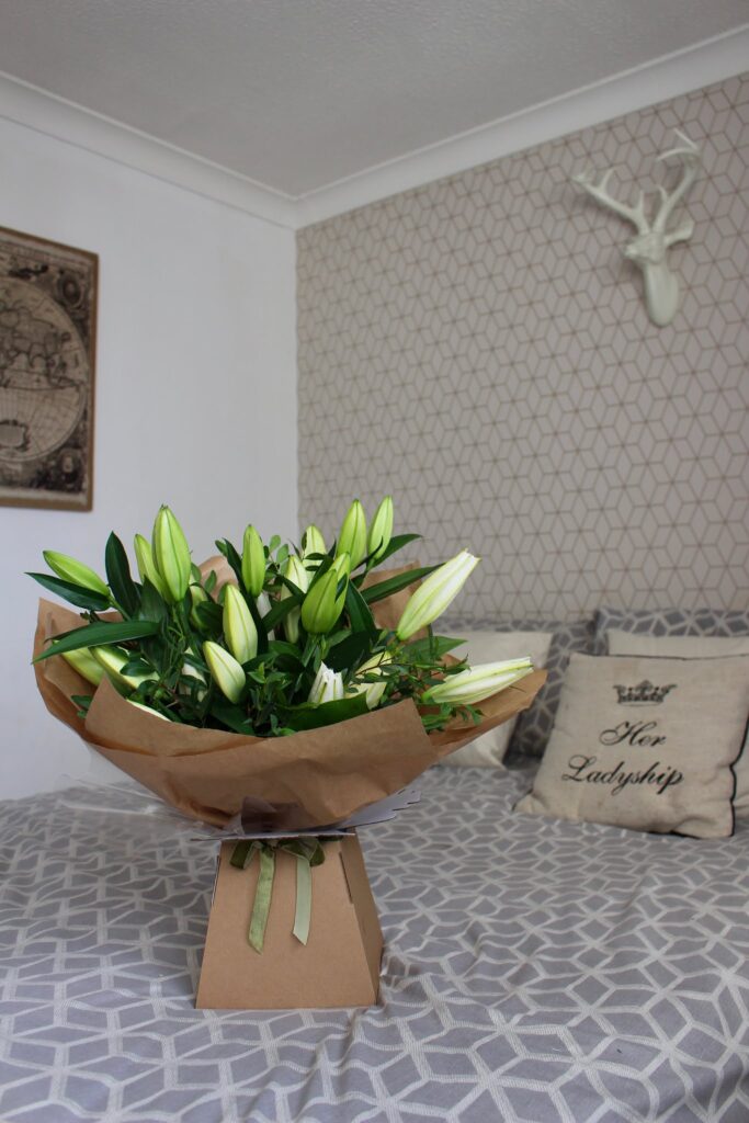 A bunch of white lilies from The Flower Shops sitting on a bed. A giveaway with The Flower Shops