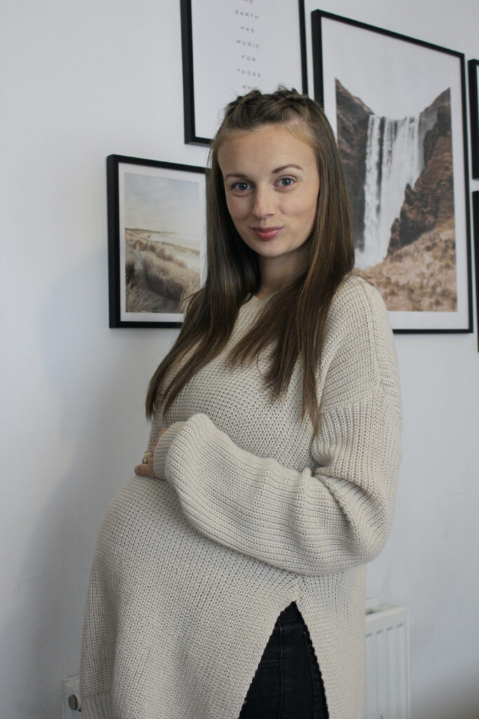 Image for what to pack in your hospital bag for labour. Claire holding third trimester bump.