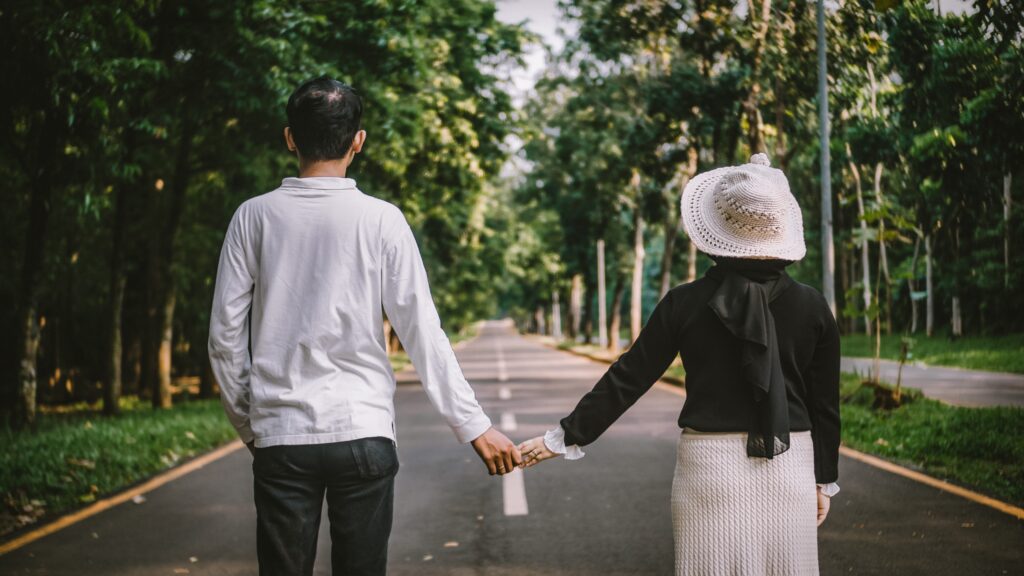 Couple holding hands looking down street.