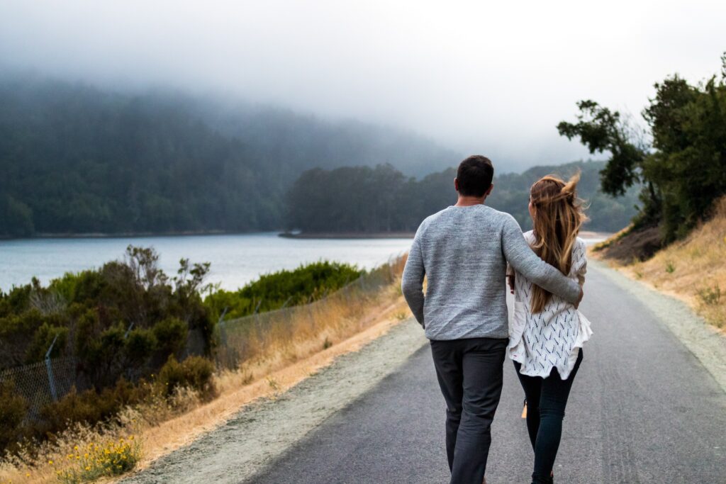 Couple walking down a road by the lake.