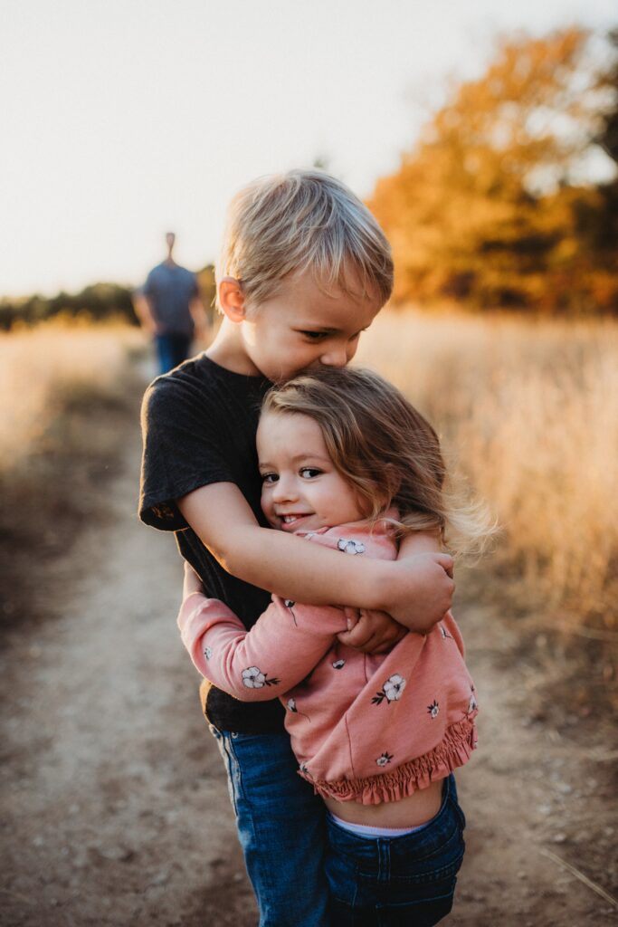 How to explore gratitude with your children. Two siblings cuddling outdoors.