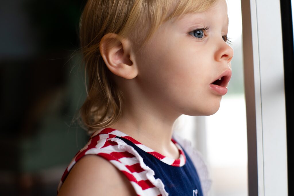 An inquisitive child looking out of a window.