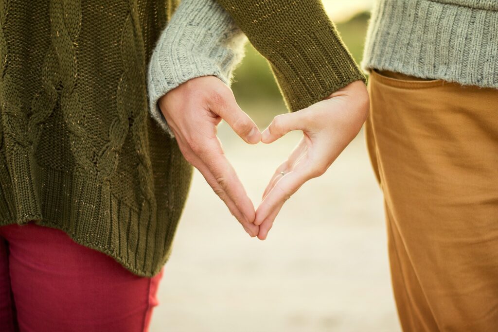 Relatioship dynamics. Couple forming love heart shape with their hands.