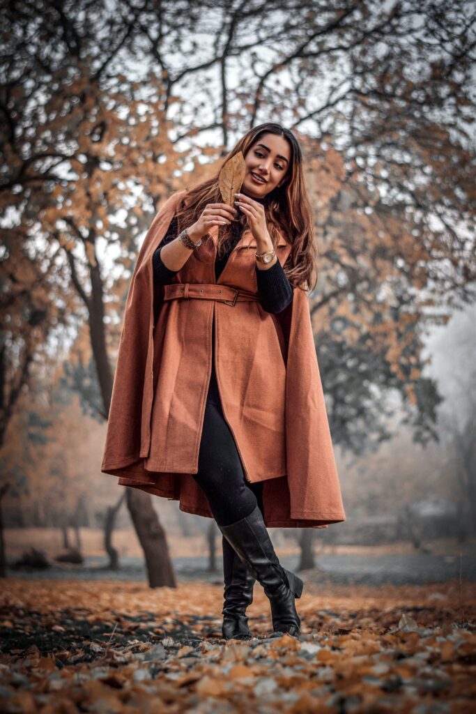Lady in autumn leaves wearing classic staples from an autumn capsule wardrobe.