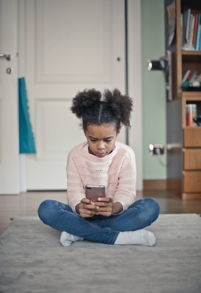Young girl playing on smartphone. This article gives tips on how you can teach children about smartphone etiquette.