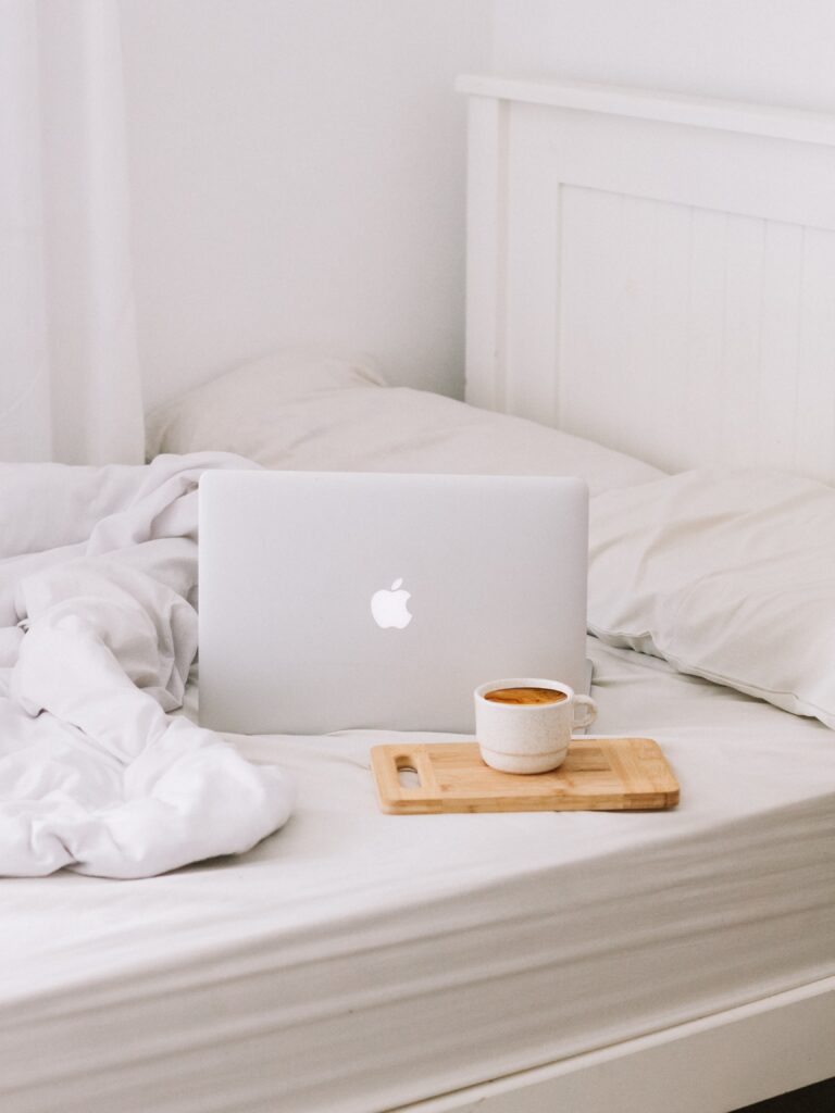 Macbook set up on bed with coffee.