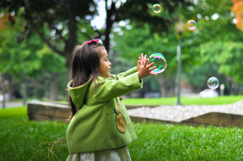 Young girl playing with bubbles. How to help your child become more independent. 