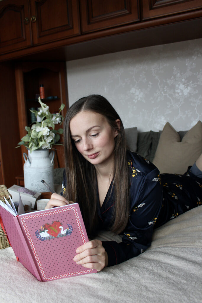 Claire Mac wearing navy bee print Chelsea Peers pyjamas writing in journal.