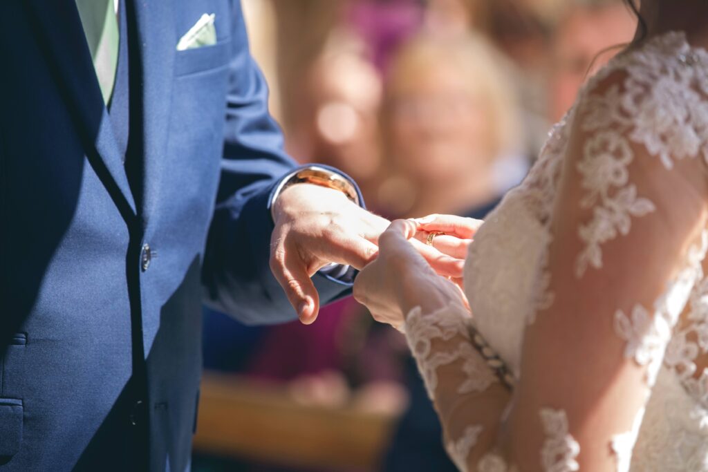 Bride placing ring on grooms finger. This post list 8 ways to maintain a happy marriage after children.