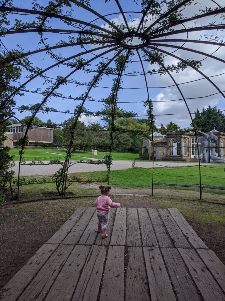 Toddler girl running through a park.