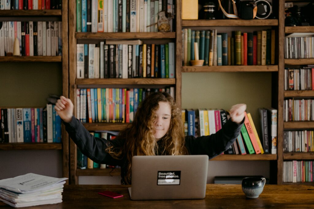 Teenage girl sat behind laptop at home doing home learning.