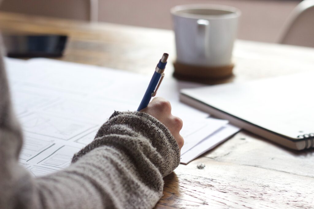 Woman holding pen writing. This is for a blog post describing ways to make learning spelling and grammar more fun.