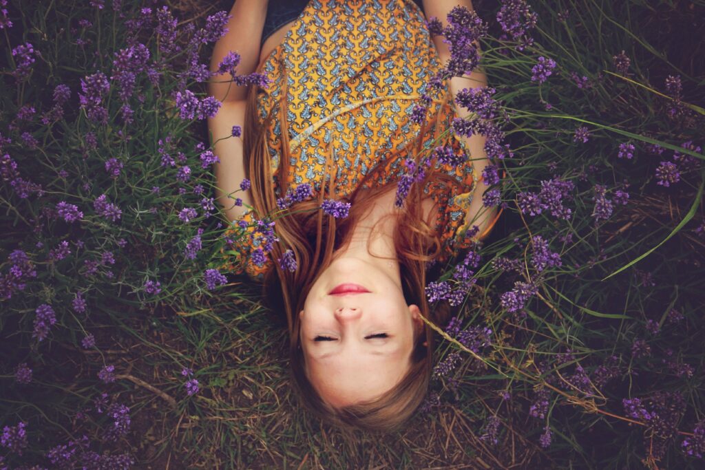 Child laying in grass amongst purple flowers. This is to go alongside a blog post discussing ways parents can encourage a growth mindset in their child.