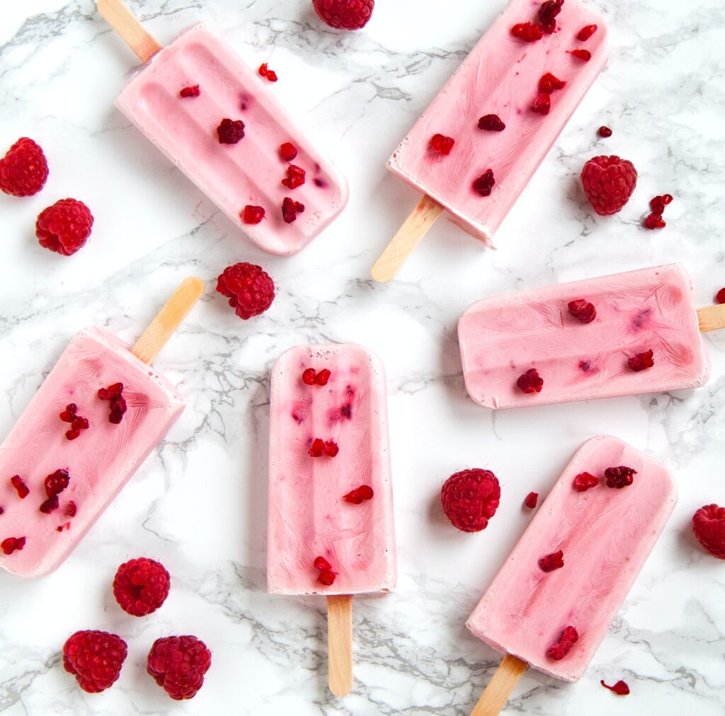 Summer themed blogging flatlay of raspberry ice lollies.