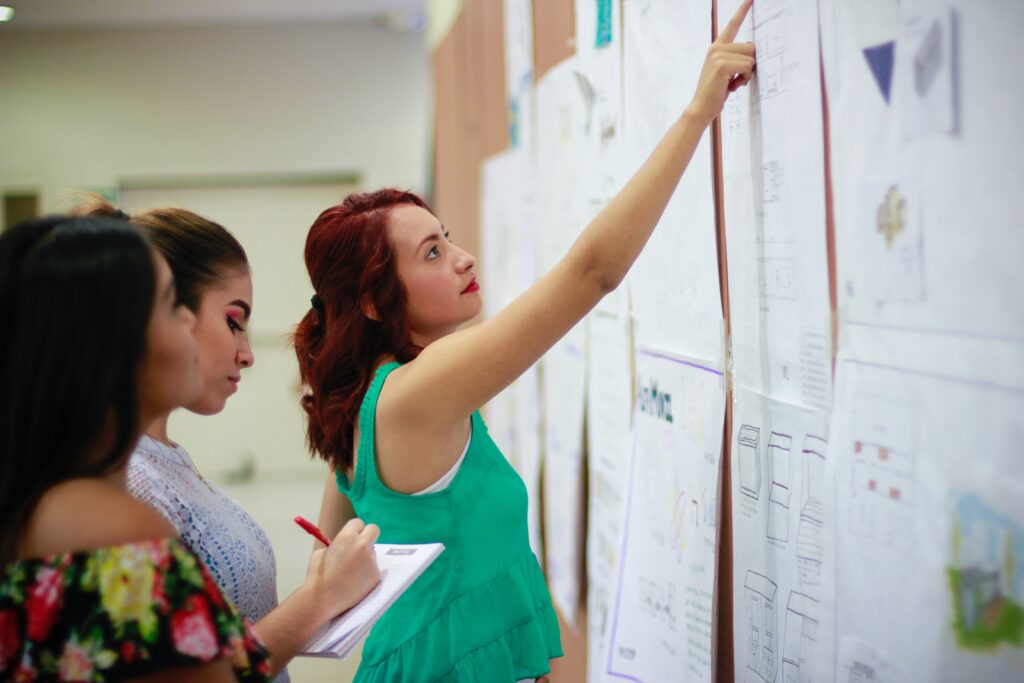Teacher pointing towards noticeboard. This is to go with a blog post discussing the power of a healthy teacher parent relationship.
