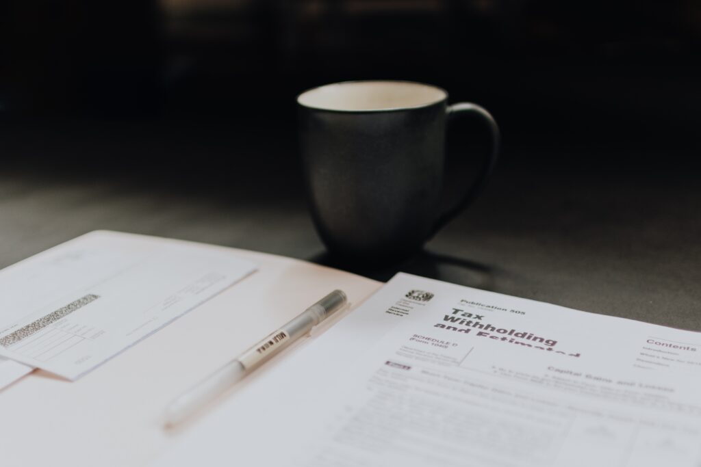 Coffee cup in focus overlooking black and white tax forms.