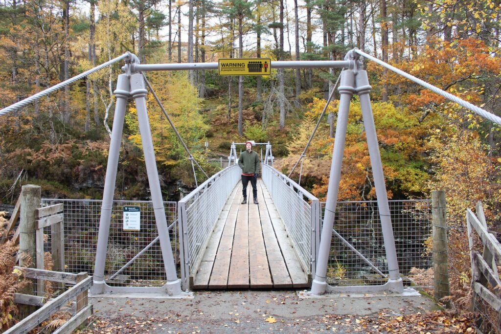 Man stood on suspension brige over Corriehsalloch Gorge in Scotland.