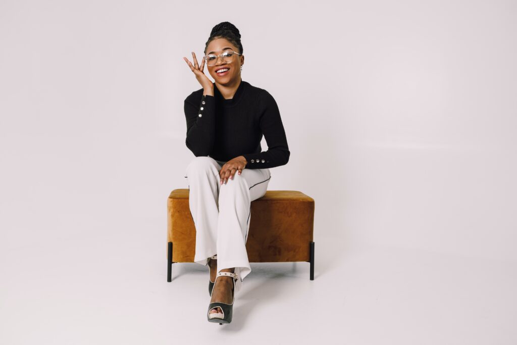 Lady sat on brown stool. This image is to go with a blog post discussing the benefits of eyeglasses.