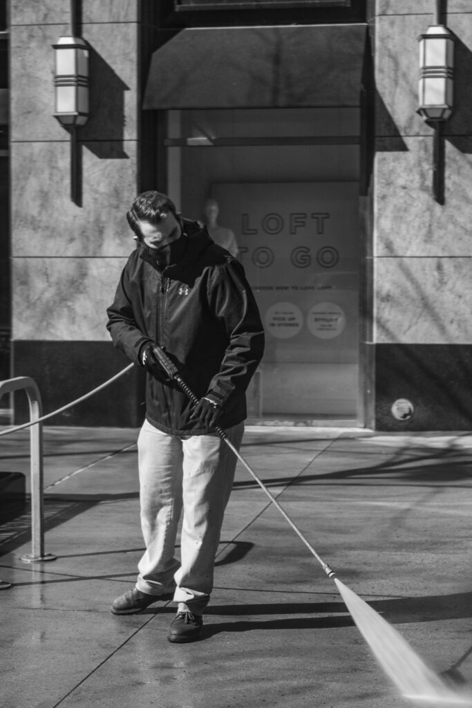 Man exterior cleaning with pressure washer on paving slabs.