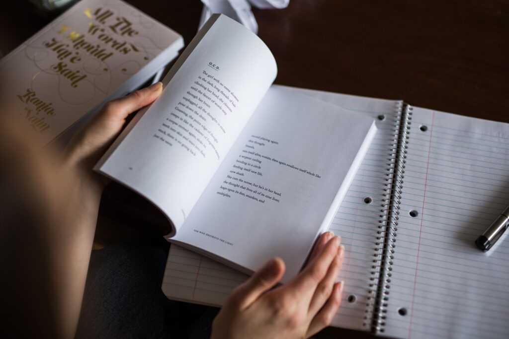 Hands holding book and notepad.
