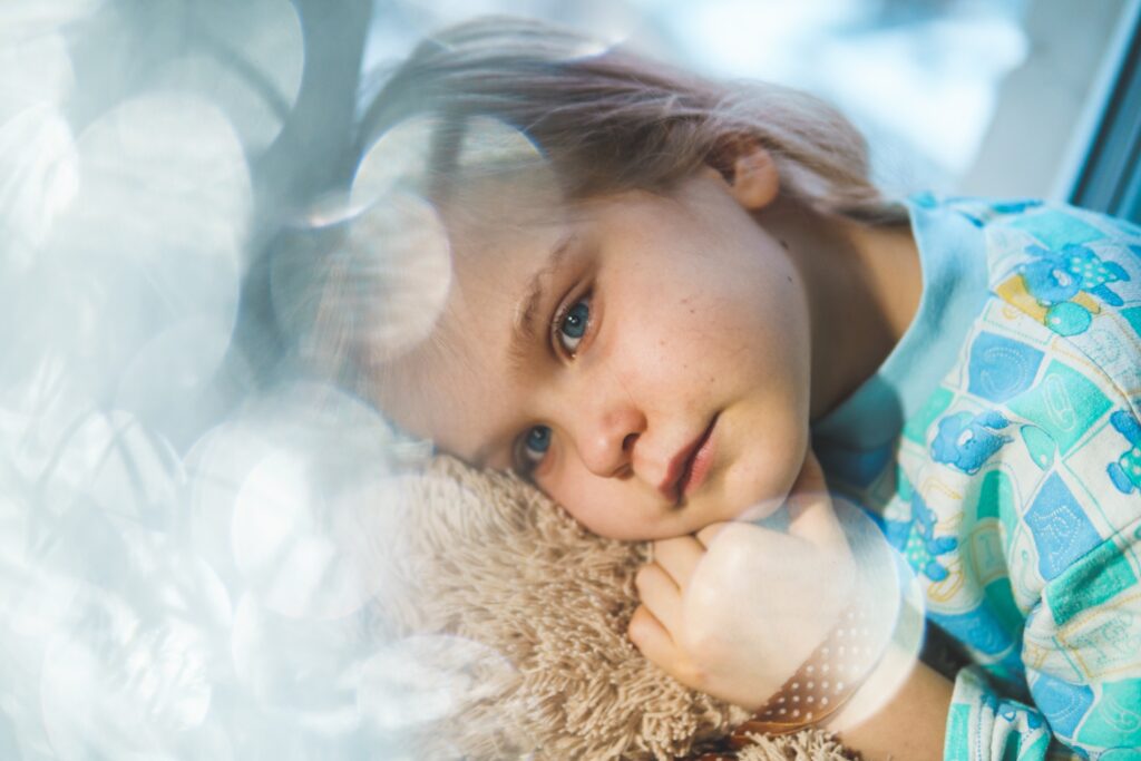 Little girl snuggling teddy bear. This is for a blog post detailing common childhood illnesses.
