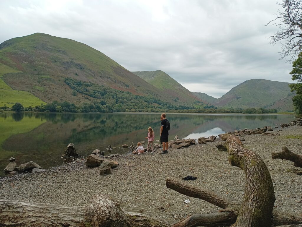 Outdoor adventures with kids. Dad and daughters at a lake in the lake district.