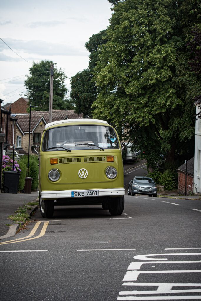 Olive green VW campervan parked up on village street.