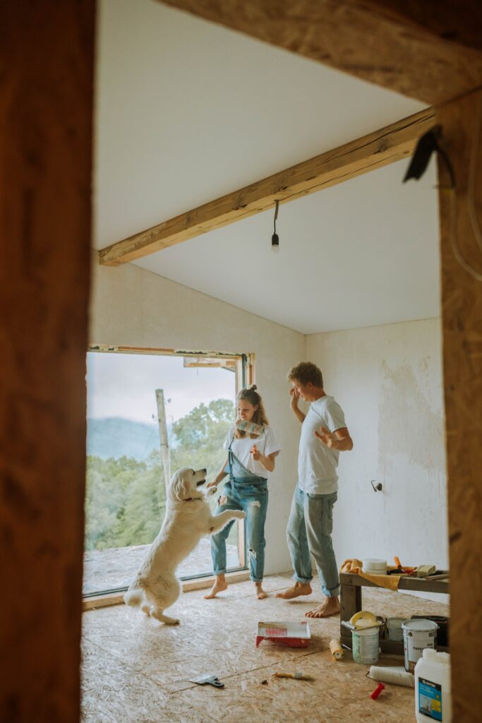 Couple dancing with dog whilst renovating their home. This is to go with an article discussing how to renovate your home on a budget.