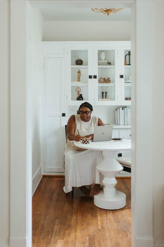 Woman sat at table working on laptop. This is to go with an article that explores when is the right time to upscale your small business.