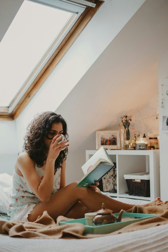 Woman sat reading a book holding coffee. This is for a post discussing physical changes that will improve your mental health.