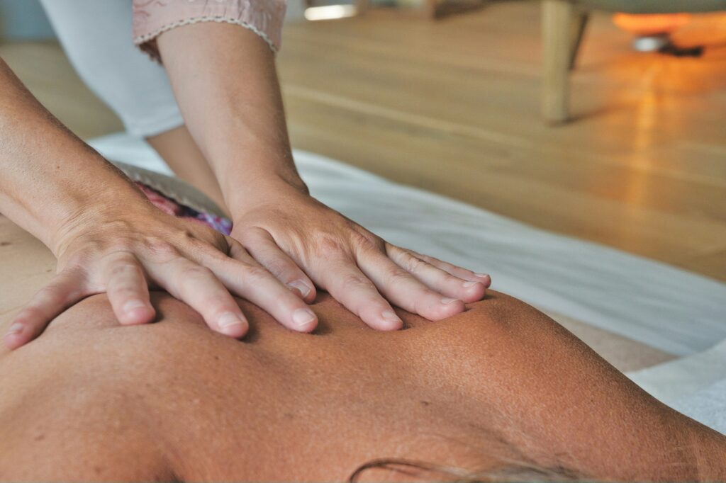 Persons hands on bare back performing massage. This is to go with an article explaining how massages relieve muscle tension.