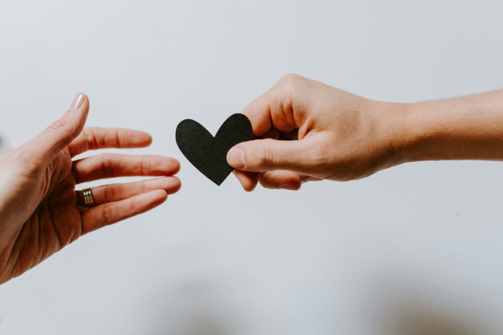 Image of one hand giving another hand a crafted heart. This is to go with a mental health post giving tips to parents of a child with BPD.