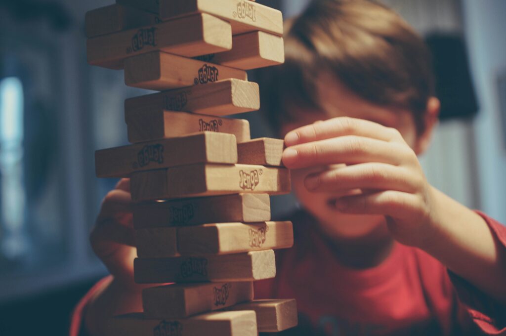 Boy playing Jenga. Jenga is one of the best board games for campervan and camping holidays.