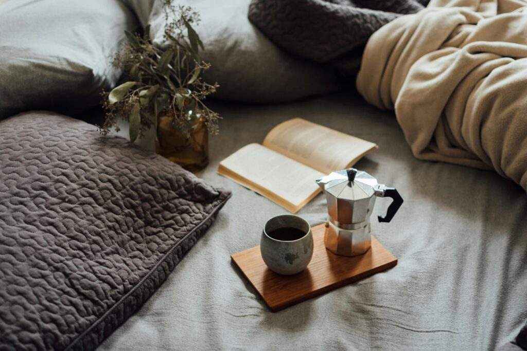Cosy bed set up with coffee and a book.