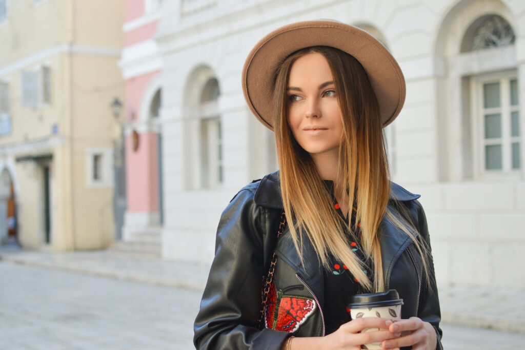 Woman wearing leather jacket and tan fedora. 5 Ways to Add Flair to Your Teacher Outfits.