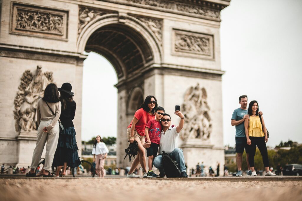 Family taking a selfie next to the arc de triomphe in France. This is to go with an article giving holiday tips for young families.