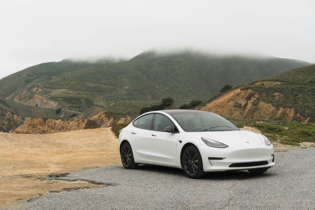 White Tesla parked up in scenic spot.