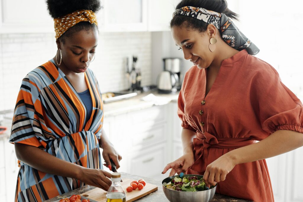 Two women sharing wellness tips while making a salad.