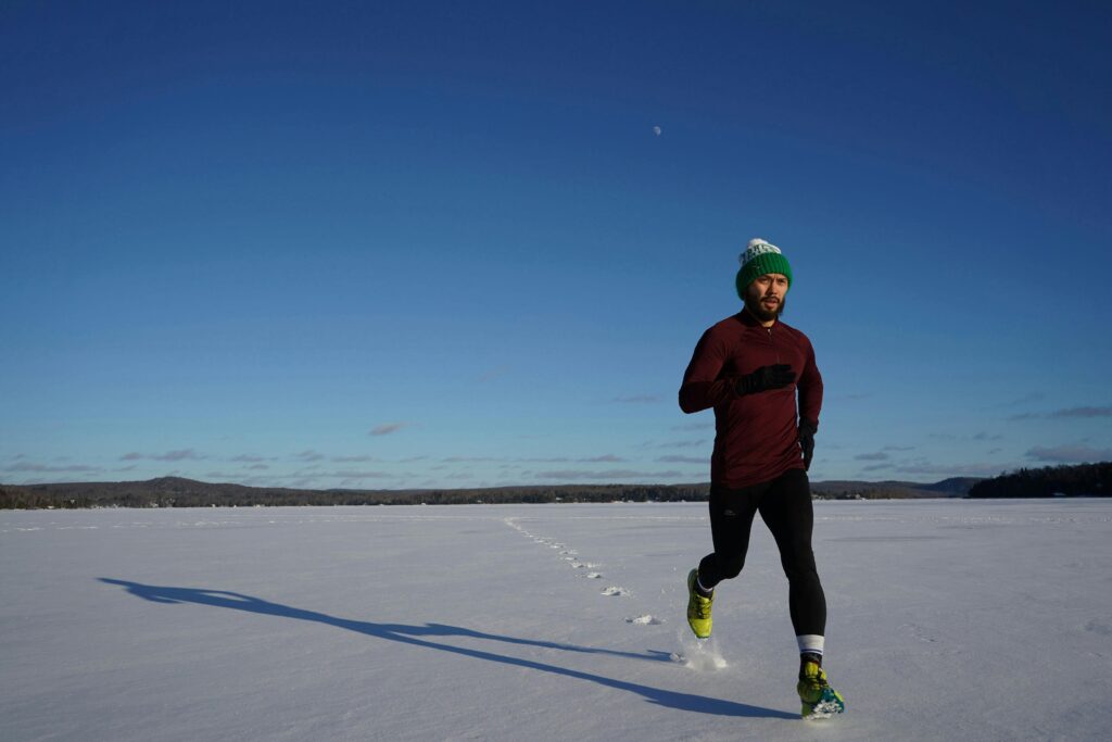 Man wearing hat running across snow.