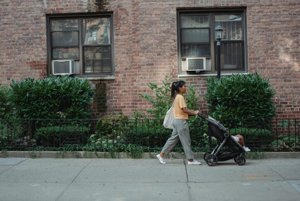 Mum pushing a pram along the street.