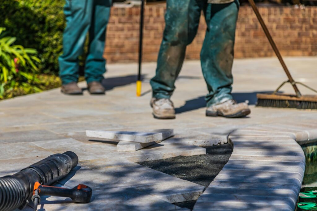 Workmen putting down porcelain paving outdoors.