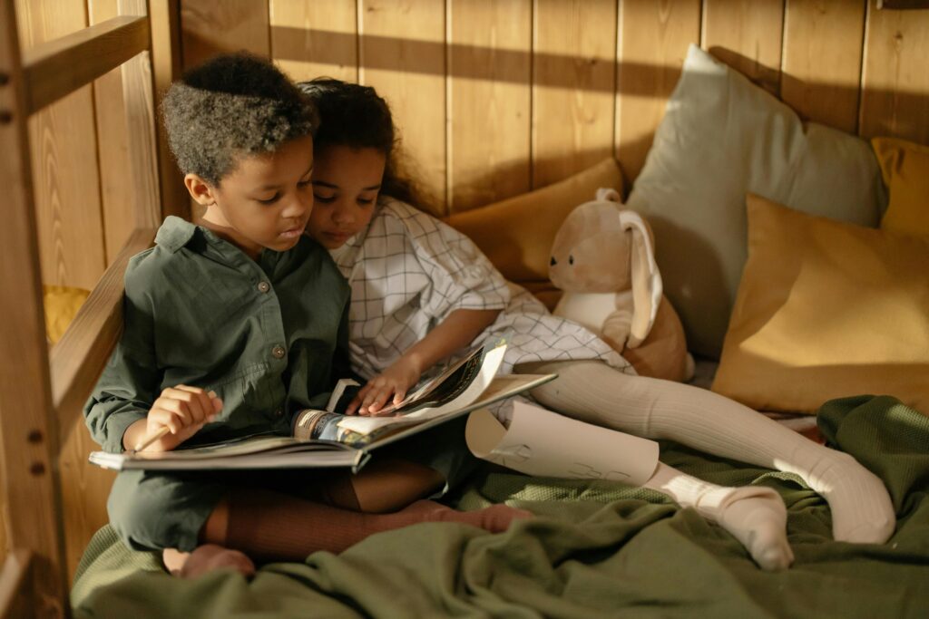 Children curled up together reading a book.