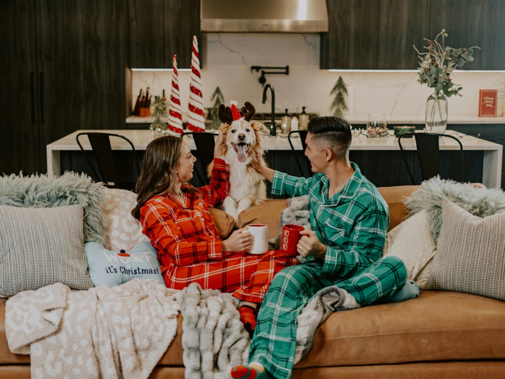 Couple with a dog, wearing Christmas pyjamas.