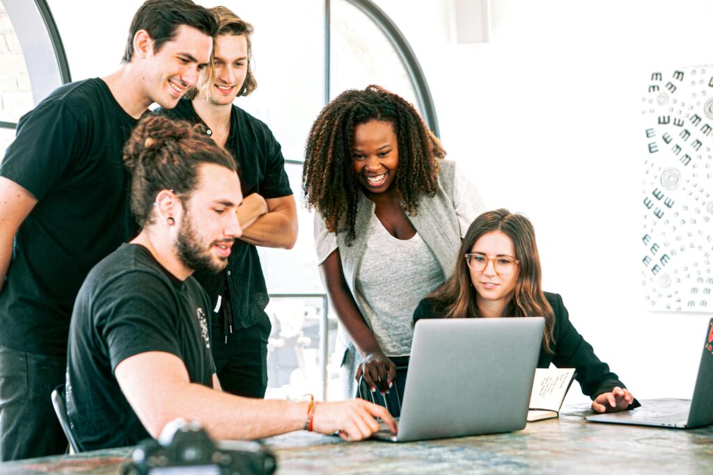 Image of work colleagues gathered around a laptop. This is to go with an article discussing mastering staff behavioural skills for professional growth.