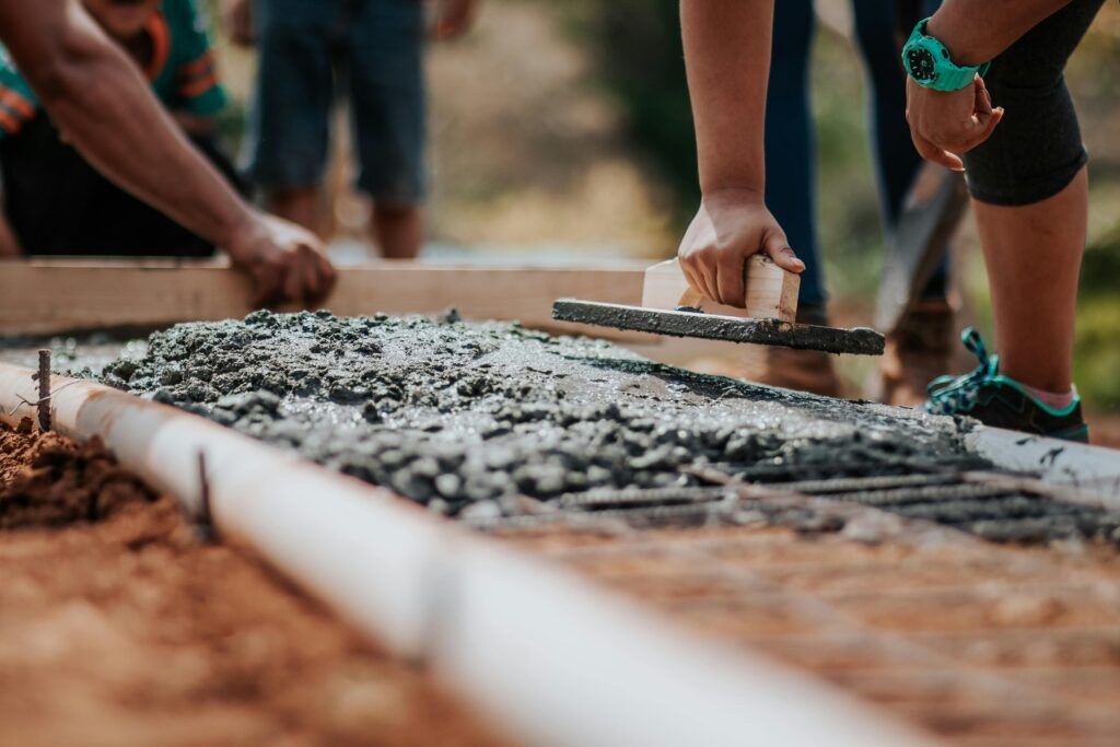 Workers using concrete equipment to lay house foundations.