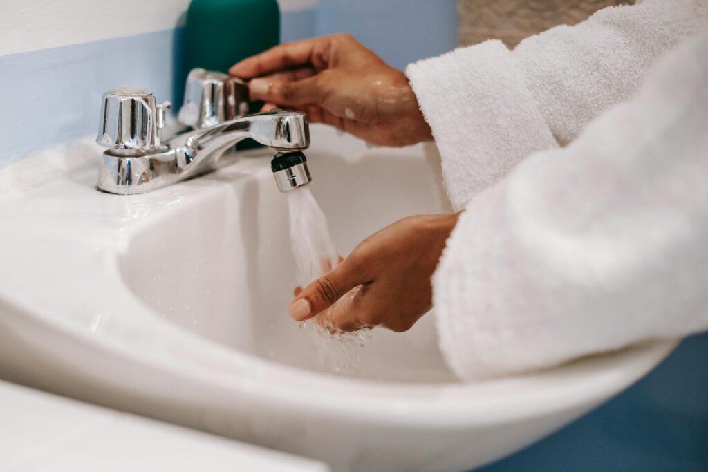 Woman washing her hands in a ceramic sink.