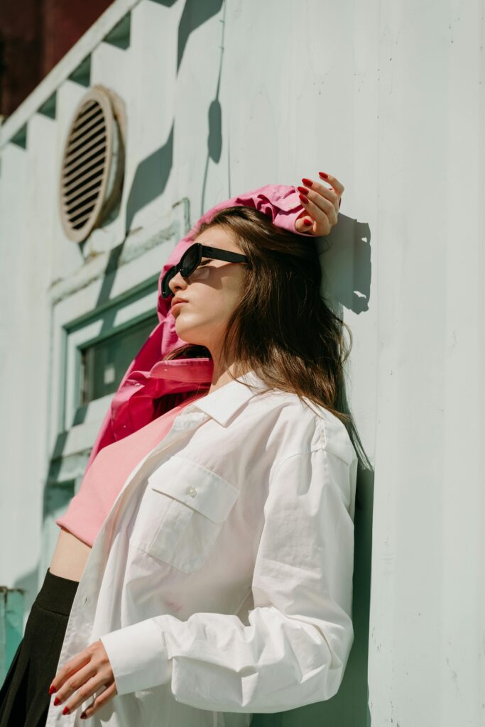 Woman wearing white and pink shirt with black sunglasses. Part of a spring capsule wardrobe.