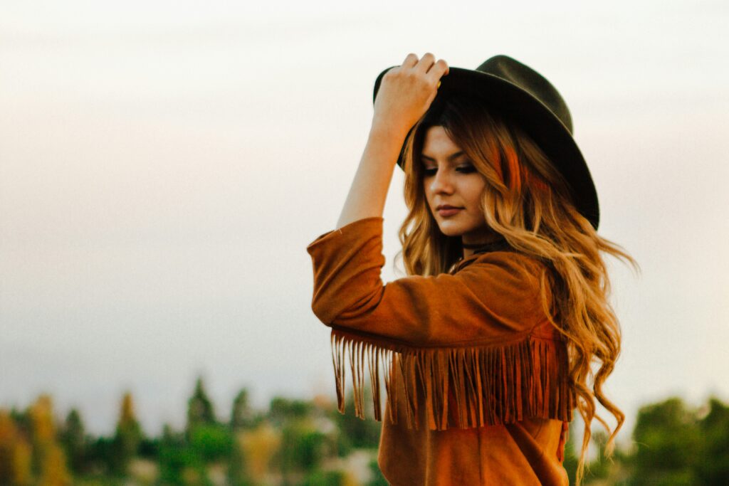 Woman wearing cowboy hat and fringed jacket line dancing.